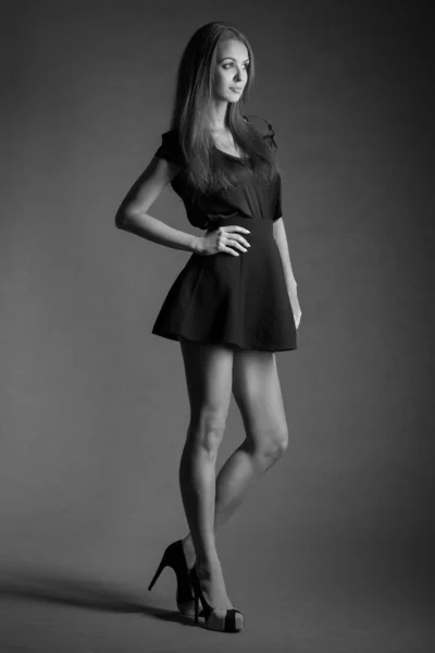 Full lenght portrait of young model woman in black short skirt and long legs