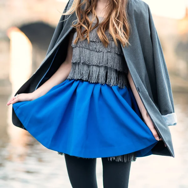 Woman street fashion look with blue skirt, jacket, dress and black tights