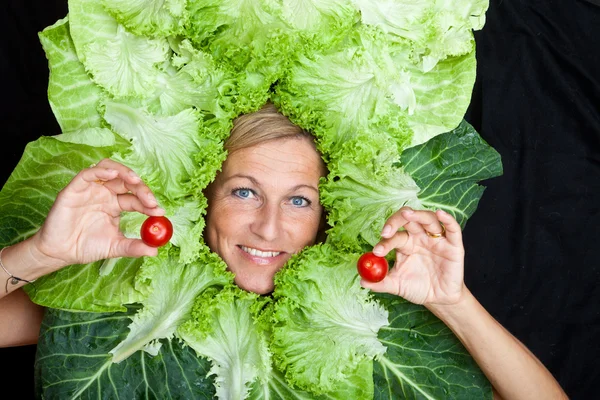 Woman with salad leaves arranged around her face