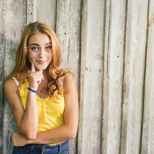 Fashion young blonde woman in yellow Tshirt over pale wooden background