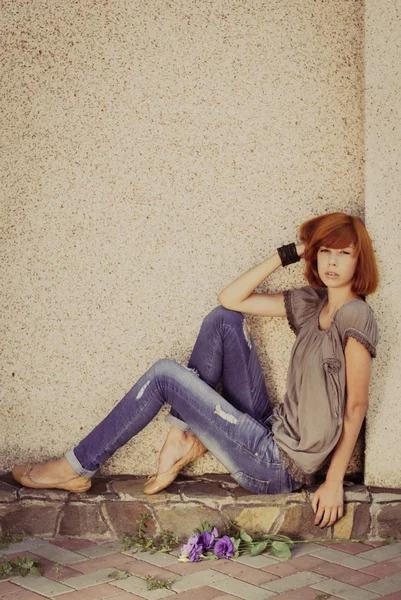 Red hair woman sitting against wall
