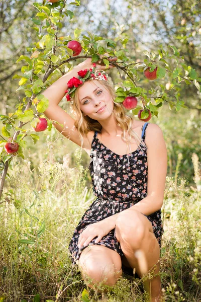 Blond girl smiling among red apples outdoors