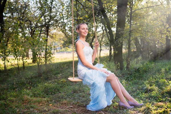 Woman in prom dress sitting on swings