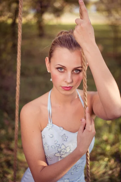 Woman in prom dress sitting on swing