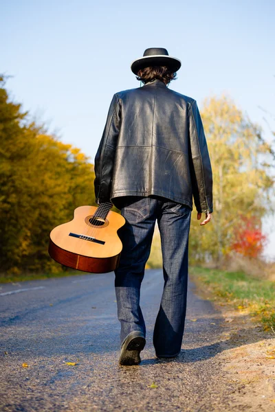 Man holding guitar and walking away