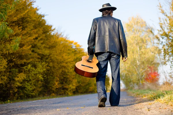 Man holding guitar and walking away