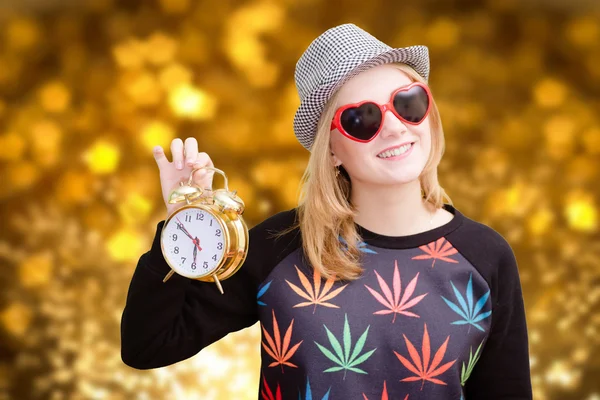 Pretty girl holding alarm clock on golden bokeh digital background