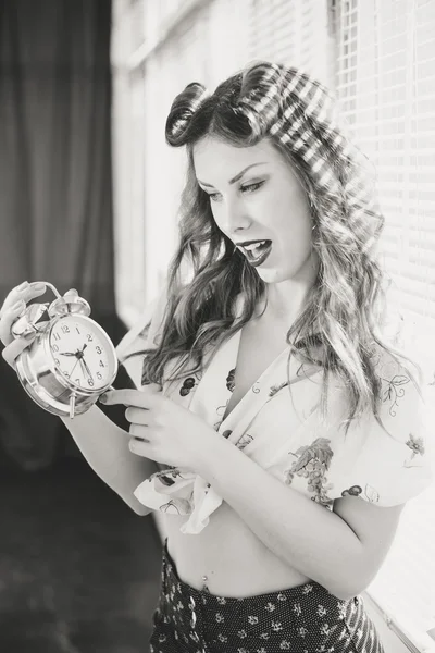 Beautiful happy smiling pinup woman showing alarm clock