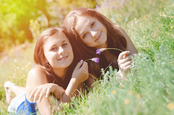 Two happy female friends playing in green grass