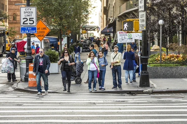People in New York cross the street at white traffic light