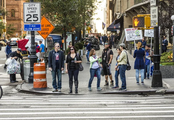 People in New York wait for green traffic light to cross the str