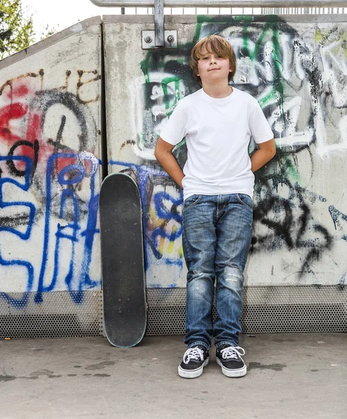 Boy relaxes with his skate board at the skate park