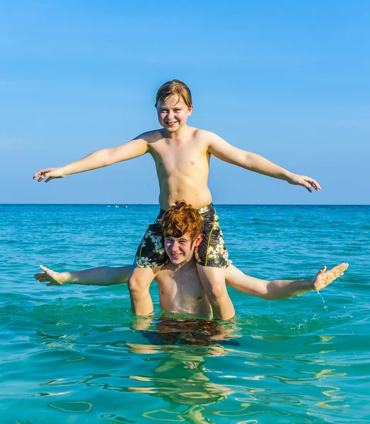 Brothers enjoying the clear warm water and play piggyback