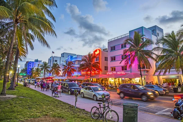 People enjoy Palm trees and art deco hotels at Ocean Drive