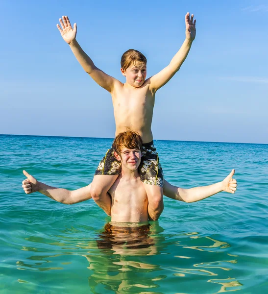 Brothers are enjoying the clear warm water in the ocean and play