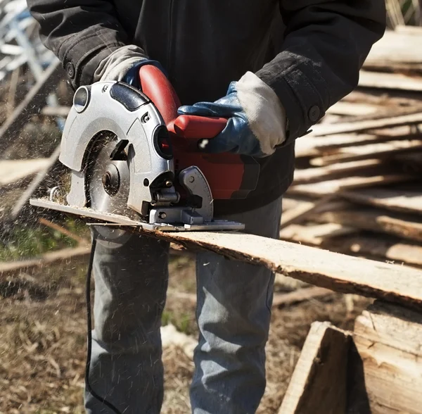 A man works outdoors with a circular saw