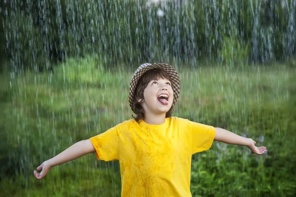 Happy boy in rain summer outdoors