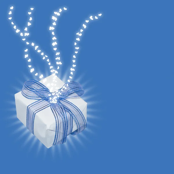 Magic gift with light rays and heart trails, on light blue background with copy space