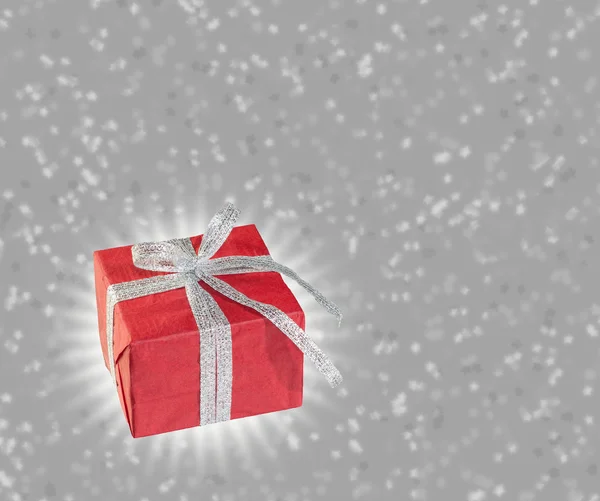 Red gift with silver ribbon on starry silver background