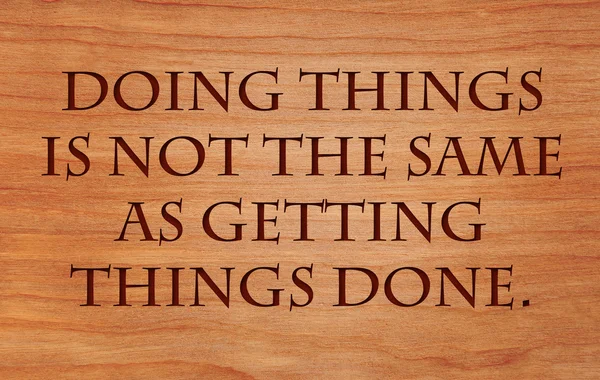 Doing things is not the same as getting things done - quote on wooden red oak background