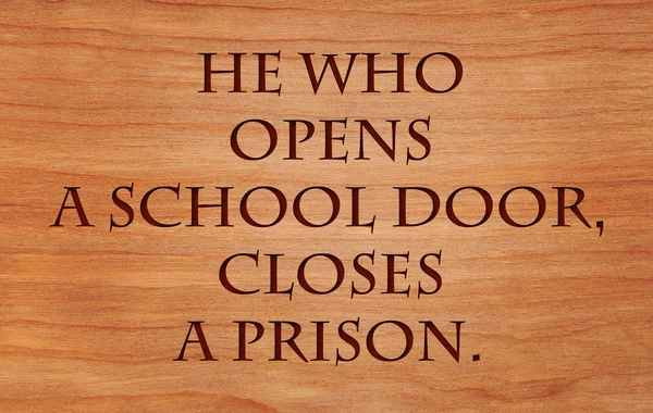 He who opens a school door, closes a prison - quote on wooden red oak background