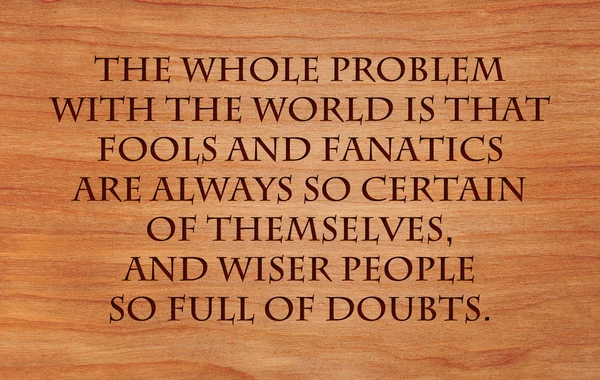 The whole problem with the world is that fools and fanatics are always so certain of themselves, and wiser people so full of doubts - quote on wooden red oak background