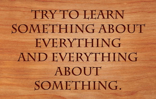 Try to learn something about everything and everything about something - quote on wooden red oak background