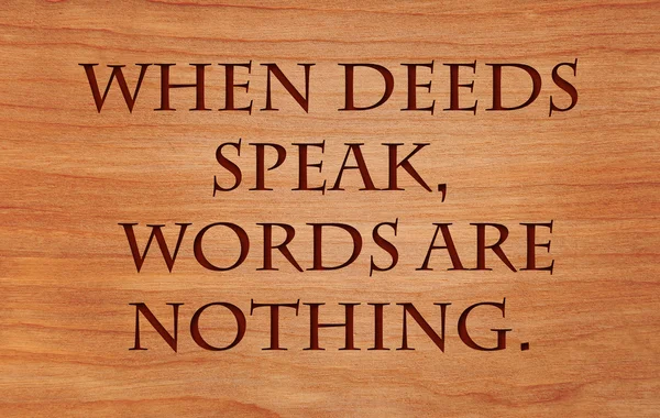 When deeds speak, words are nothing - motivational African Proverb on wooden red oak background