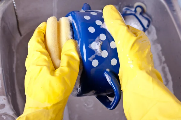 Washing dishes in yellow gloves