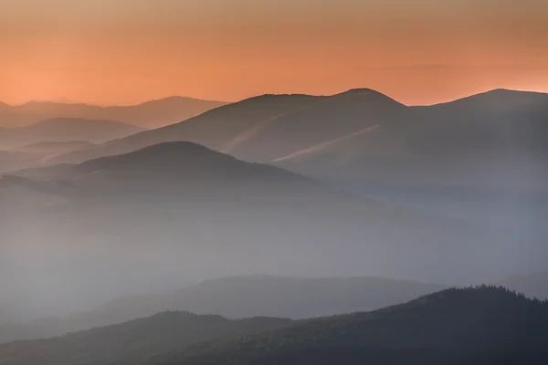 Distant mountain range and thin layer of clouds on the valleys