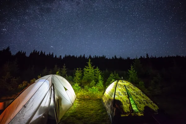 Illuminated camping tent under stars at night
