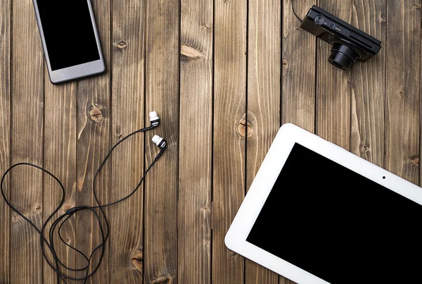 Tablet pc, smart phone, photo camera and headset on wooden background