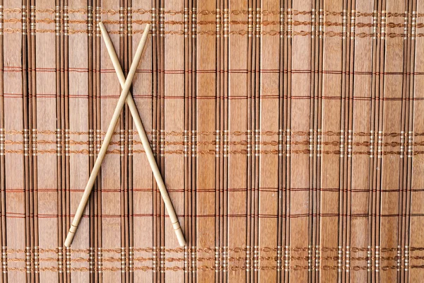 Chopsticks and sushi roll on bamboo mat. background menu