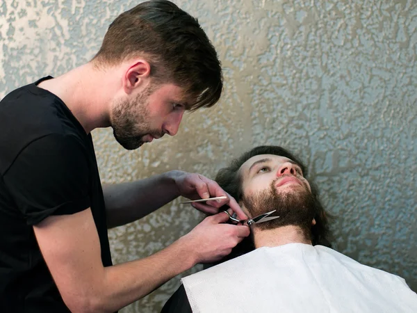 A barber  shaving man\'s beard