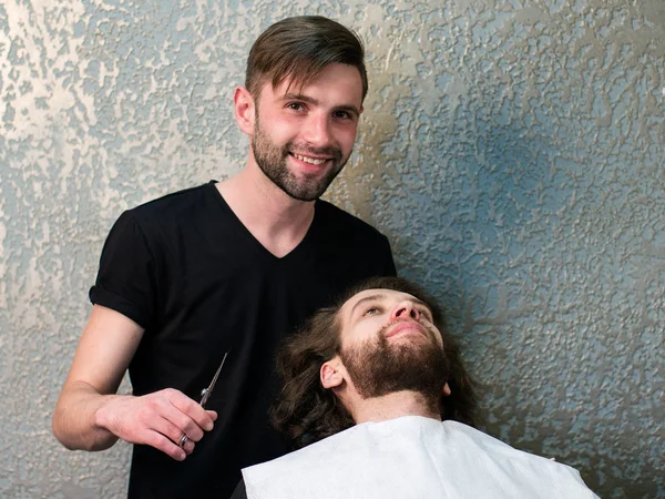 A barber  shaving man\'s beard
