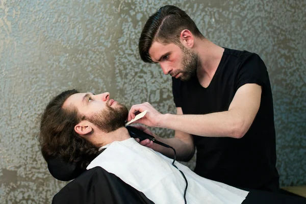 A barber  shaving man's beard