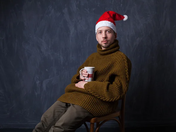Christmas studio portrait of a bearded guy in a red cap