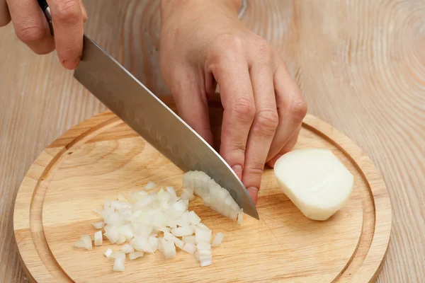 Cutting the vegetables with a kitchen knife on the board