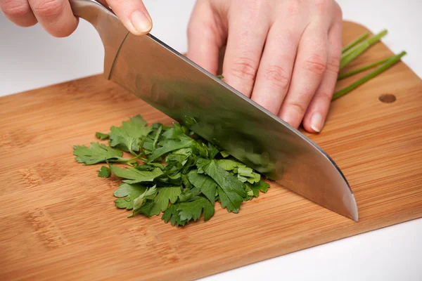 Cutting the vegetables with a kitchen knife on the board