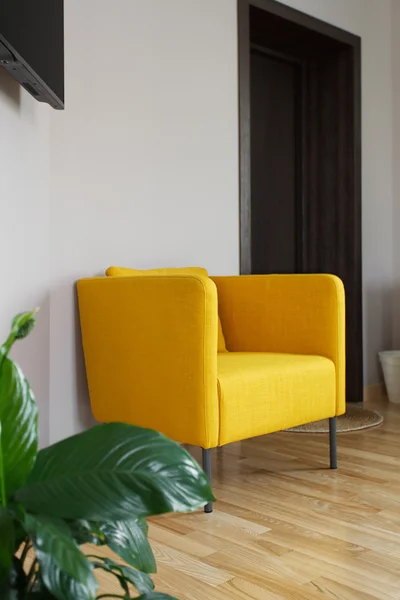 Yellow armchair near white wall