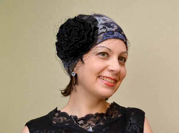 Portrait of the woman of average years in a hat with a veil on a light background