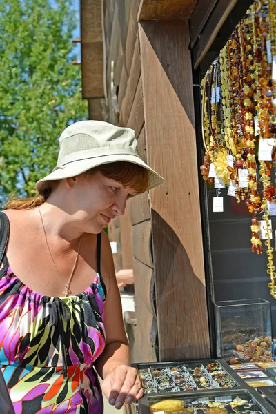 The woman of average years chooses amber jewelry in a booth