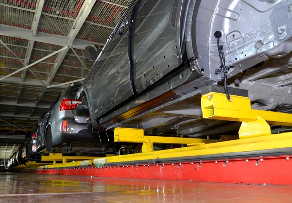 Cars stand on the conveyor line of assembly shop. Automobile pla