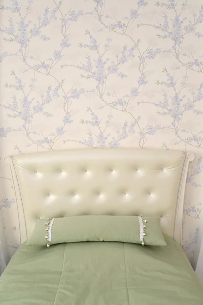 Headboard of a single bed with a throw pillow. Modern classics w