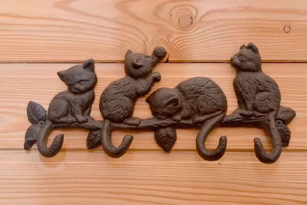 Metal hanger with hooks in the form of kittens on a wooden wall