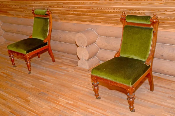 Two soft chairs with a velvet upholstery stand near a timbered w