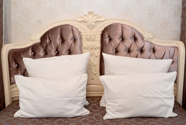 Carved headboard of a double bed with pillows