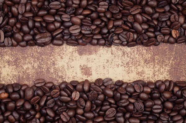 Dark roasted coffee beans arranged in a frame on a grunge faux l