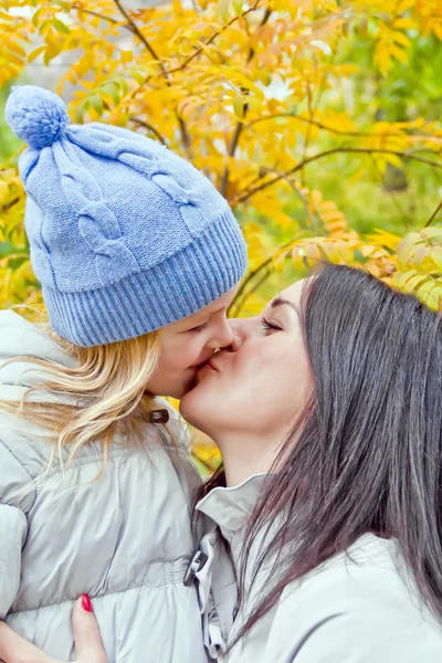 Mother and daughter kiss in autumn