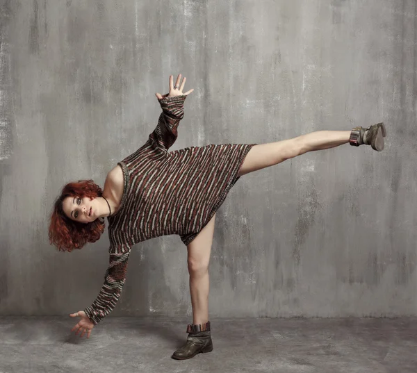 Red-haired girl in a big knitted sweaters and boots standing on